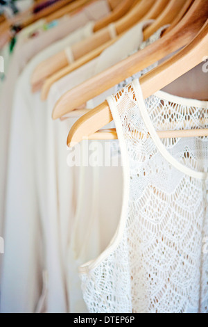 Row of white and ivory blouses on wooden hangers Stock Photo