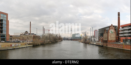 Looking westward to the Berlin TV tower on bridge over river Spree overcast doom and gloom reflection in calm waterway industry Stock Photo