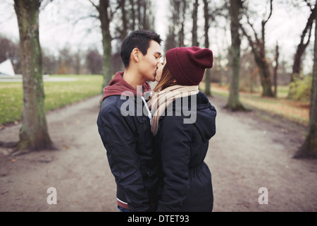 Loving young couple kissing outdoors in the park. Mixed race man and woman. Teenage love. Stock Photo