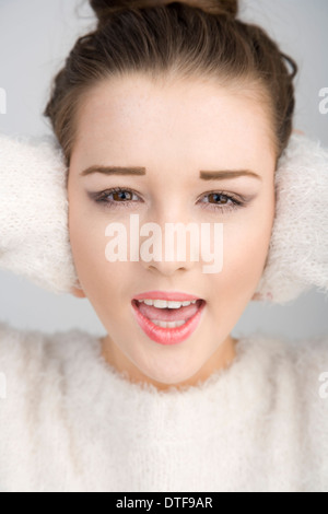 A pretty teenage girl shouting with her hands over her ears. Stock Photo