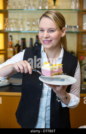Waitress presenting a piece of cake in café Stock Photo