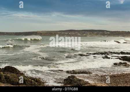 WAVES BREAKING ON THE SHORE AT CULLEN BAY MORAY WITH CULLEN TOWN IN THE DISTANCE