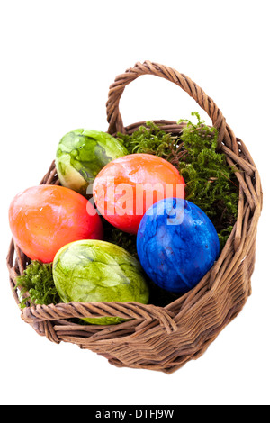 Rustic wicker basket of brightly coloured hand-painted traditional Easter Eggs with a marbled pattern nestling in a bed of green moss, high angle view isolated on white Stock Photo