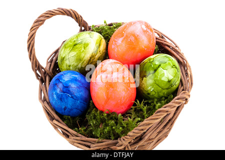 Rustic wicker basket of brightly coloured hand-painted traditional Easter Eggs with a marbled pattern nestling in a bed of green moss, high angle view isolated on white Stock Photo