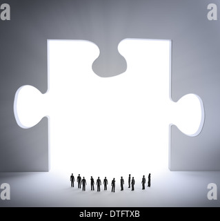 Tiny people looking and a jigsaw puzzle piece Stock Photo