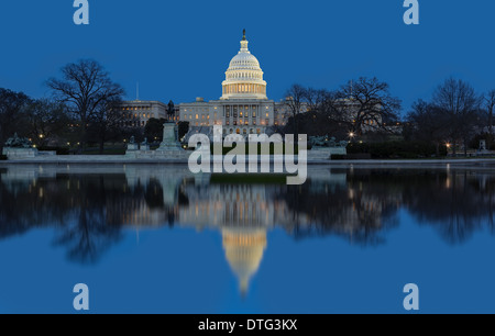 A west side view at twilight  of the regal dome and building of the United States Capitol in Washington DC. The stilled winds after sunset reflects the majestic building in the pool of water. Stock Photo