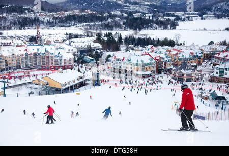 Mont-Tremblant, Canada - February 9, 2014: Skiers and snowboarders are sliding down the main slope at Mont-Tremblant. Stock Photo