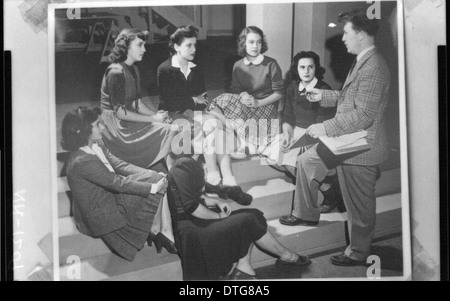A historical photograph capturing a lecture on the steps, with students engaged in discussion or listening. The scene reflects the educational atmosphere at Miami University, showcasing the importance of women's education and academic engagement during the early 20th century. Stock Photo