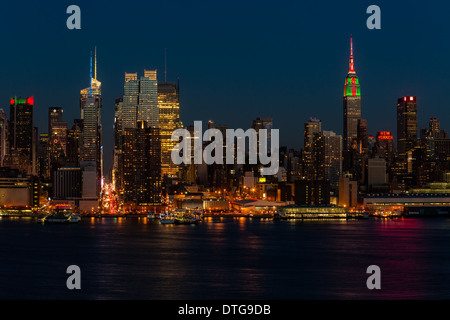 The New York City Skyline and the Empire State Building illuminated in red, green and white in celebration of the Christmas Holiday. The ESB antenna is lit up in red and white the colors of a candy cane. The New York City Skyline as viewed from New Jersey across the Hudson River during the blue hour.