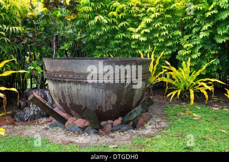 An ancient cast iron cauldron rests on a fire pit ready to burn. Stock Photo