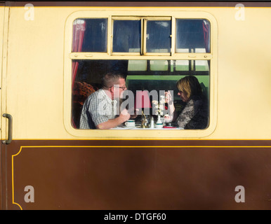 A man and woman enjoy lunch on a North Yorkshire Moors Railway Pullman Dining Train at Goathland February 2014 Stock Photo