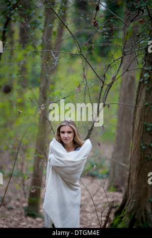 woman in a forest wrapped in a blanket Stock Photo