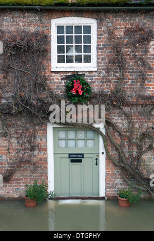A Victorian red brick Water Mill building with flood water coming up over the sand bags on the door step. Stock Photo