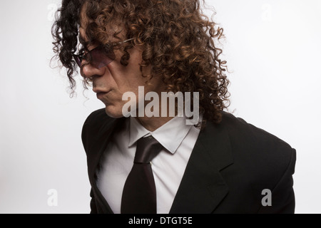 Cropped portrait of mediterranean looking man with curly hair wearing business suit and sun glasses Stock Photo