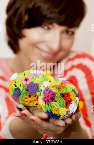 Young smiling woman holding in the hands two easter eggs made of colored paper. Stock Photo
