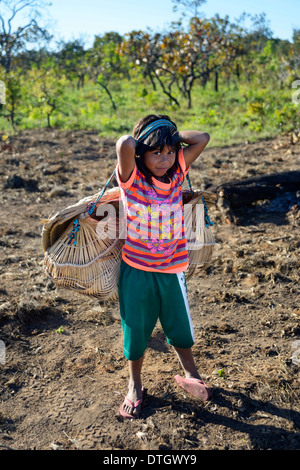 Girl carrying her little sister in a traditional basket on her back, village of the Xavantes people, Nova Vida near the mission Stock Photo
