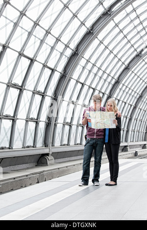 Young couple standing on the platform and looking at a map, Berlin, Germany Stock Photo