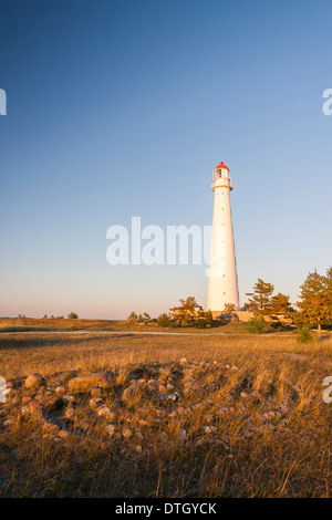 Tall slim white beacon or lighthouse known as Tahkuna at sunset in Hiiumaa, Estonia and stone labyrinth or maze in foreground. Stock Photo