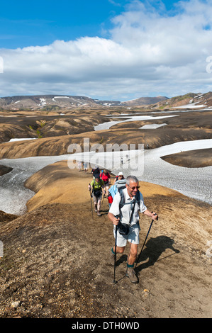Trekking in the highlands, hiking group on a trail across snowfields, Laugavegur hiking trail, near Hrafntinnusker Stock Photo