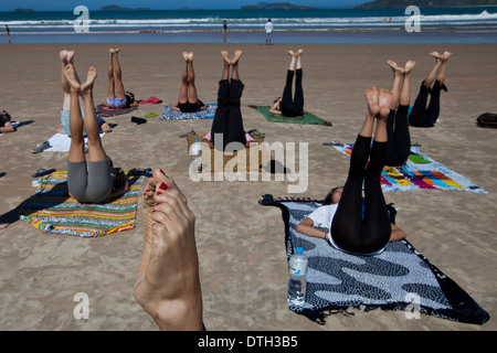 Young people practicing yoga at Geriba beach, Armacao de Buzios, Rio de Janeiro State, Brazil. Stock Photo