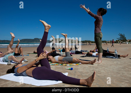 Young people practicing yoga at Geriba beach, Armacao de Buzios, Rio de Janeiro State, Brazil. Flexibility and elasticity Stock Photo