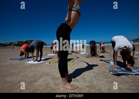 Young people practicing yoga at Geriba beach, Armacao de Buzios, Rio de Janeiro State, Brazil. Beautiful thin woman lean belly Stock Photo