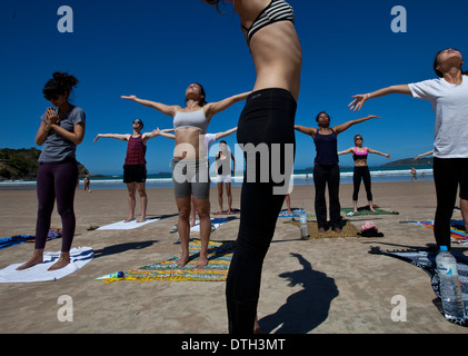 Young people practicing yoga at Geriba beach, Armacao de Buzios, Rio de Janeiro State, Brazil. Beautiful thin woman lean belly Stock Photo