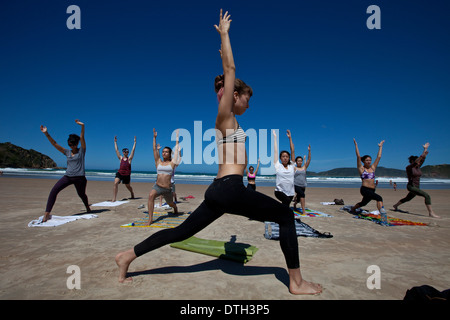 Young people practicing yoga at Geriba beach, Armacao de Buzios, Rio de Janeiro State, Brazil. Beautiful thin woman lean belly Stock Photo