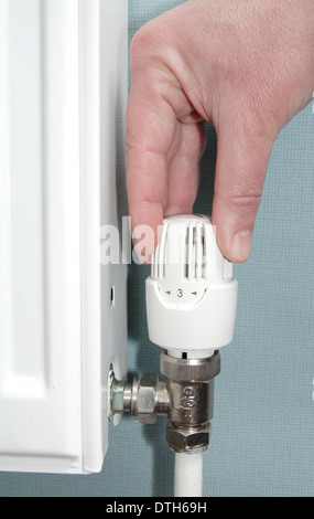 Man turning radiator valve/heating control up down in lounge of domestic home, England, UK (model released) Stock Photo
