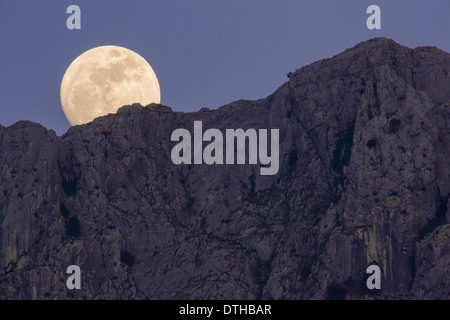 Real full moon rising over Serra d'Alfàbia mountain at dusk. Tramuntana hills, Sóller area, Majorca, Balearic islands, Spain