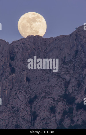 Real full moon rising over Serra d'Alfàbia mountain at dusk. Tramuntana hills, Sóller area, Majorca, Balearic islands, Spain