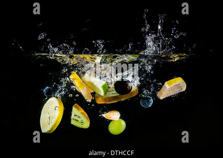 Splashing fresh fruit on water on black background Stock Photo
