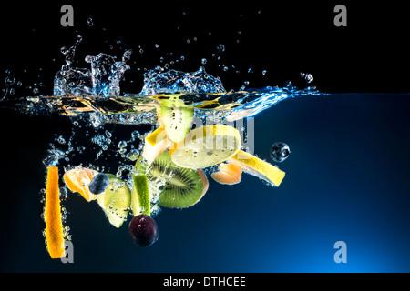 Splashing fresh fruit on water on black background Stock Photo