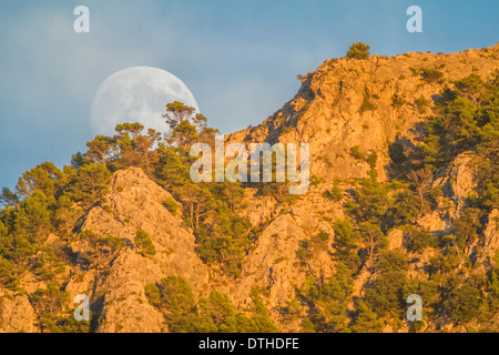 Real full moon rising over Puig des Teix mountain at sunset. Tramuntana mountains, Deià, Majorca, Balearic islands, Spain