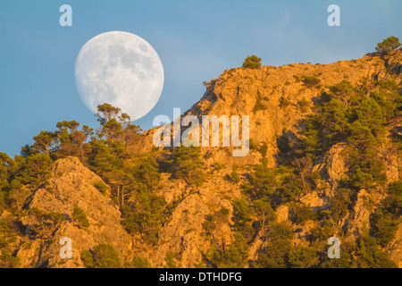 Real full moon rising over Puig des Teix mountain at sunset. Tramuntana mountains, Deià, Majorca, Balearic islands, Spain