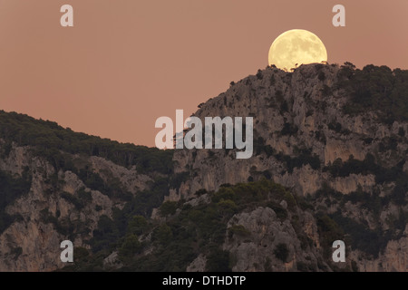Real full moon rising over Penyal d'Honor mountain at dusk. Tramuntana hills, Bunyola area, Majorca, Balearic islands, Spain
