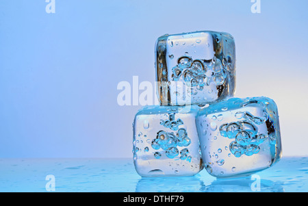 Three ice cubes on blue background Stock Photo