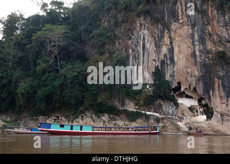 Passenger boat and tourists along the Pak Ou Caves on the Mekong River in Laos. Stock Photo