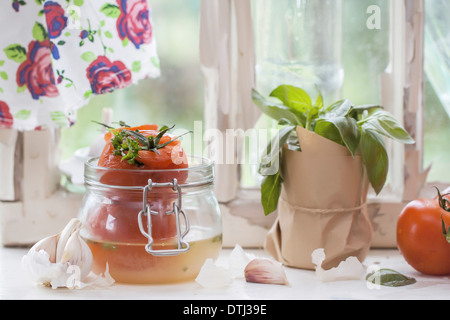 Canned tomatoes and basil on old windowsill in nature light Stock Photo