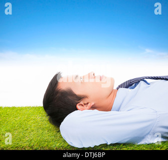 young businessman lying on a meadow and contemplating Stock Photo