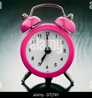 pink Alarm clock close up on bedside table Stock Photo