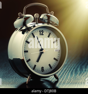 metallic Alarm clock on bedside table in morning light Stock Photo