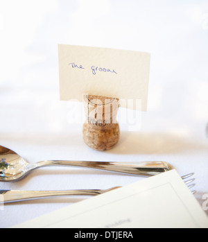 Top table at a wedding banquet An upside down cork with name tag for the groom Silver fork and spoon England Stock Photo