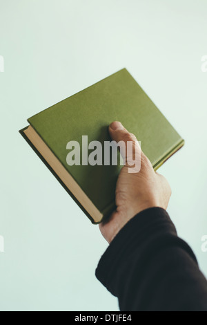 a man holding a hardback book green cover Stock Photo