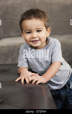 A child leaning on a brown chair looking at the camera smiling  Pennsylvania USA Stock Photo