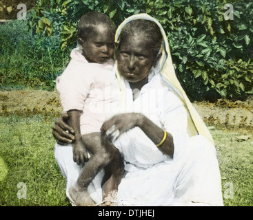 An elderly woman and a baby are depicted in a photograph from India, circa 1920. The image provides a glimpse into familial relationships and generational care in early 20th-century India. Stock Photo