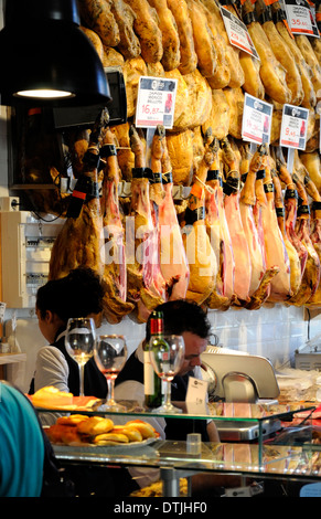 Madrid, Spain. Mercado de San Miguel (covered ironwork market - 1916) Whole hams / Jamon Iberico on sale - wineglasses on bar Stock Photo