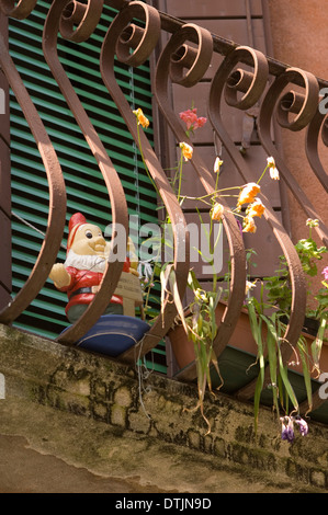 Garden gnome on balcony with wrought iron metal railings, detail. Stock Photo