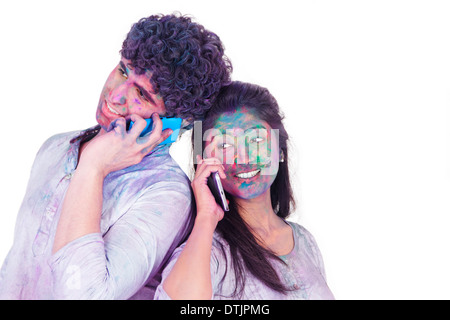 Couple talking on mobile phones on Holi Stock Photo