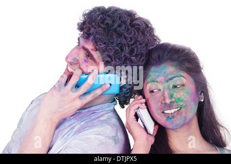 Couple talking on mobile phones on Holi Stock Photo